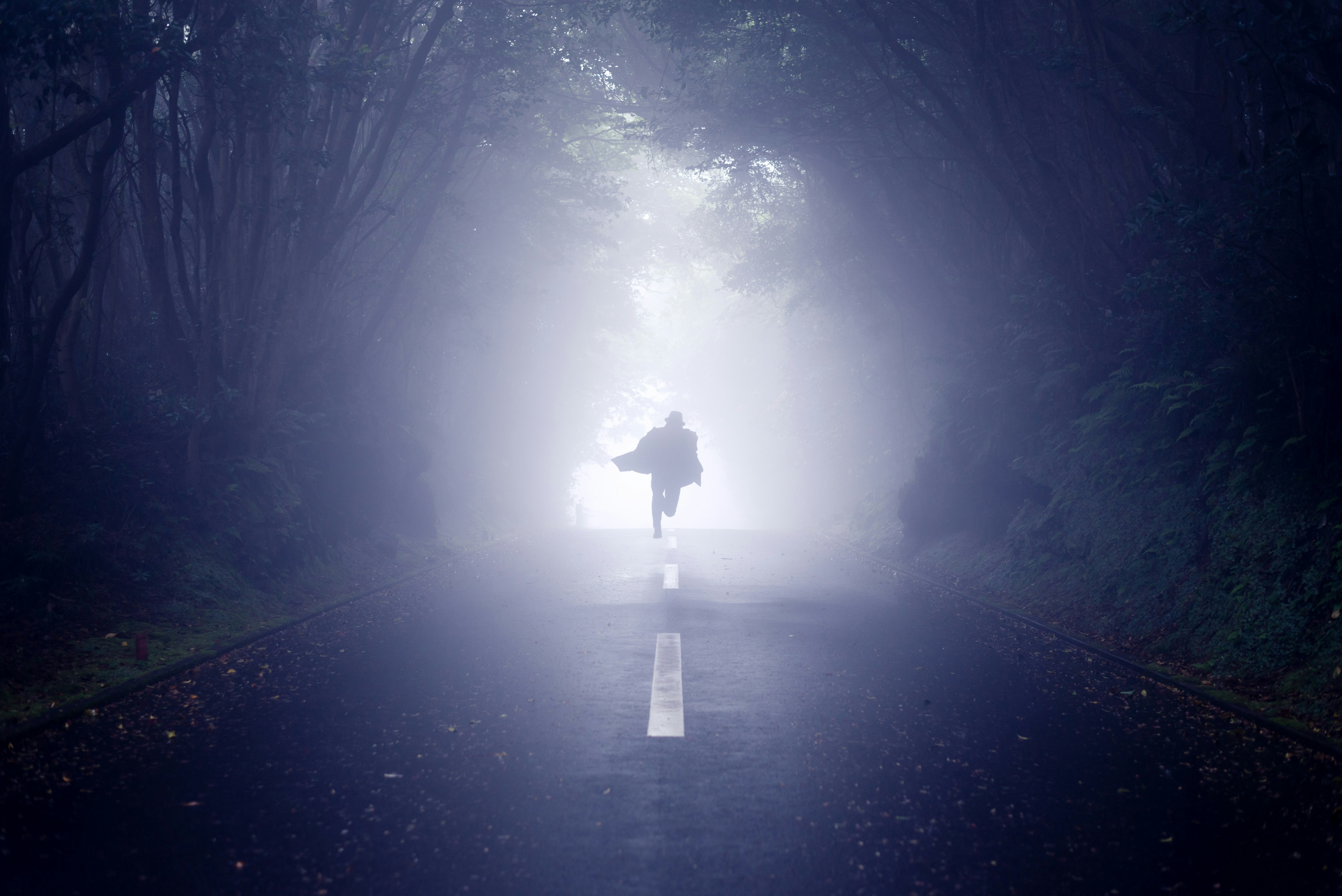 person running road between trees